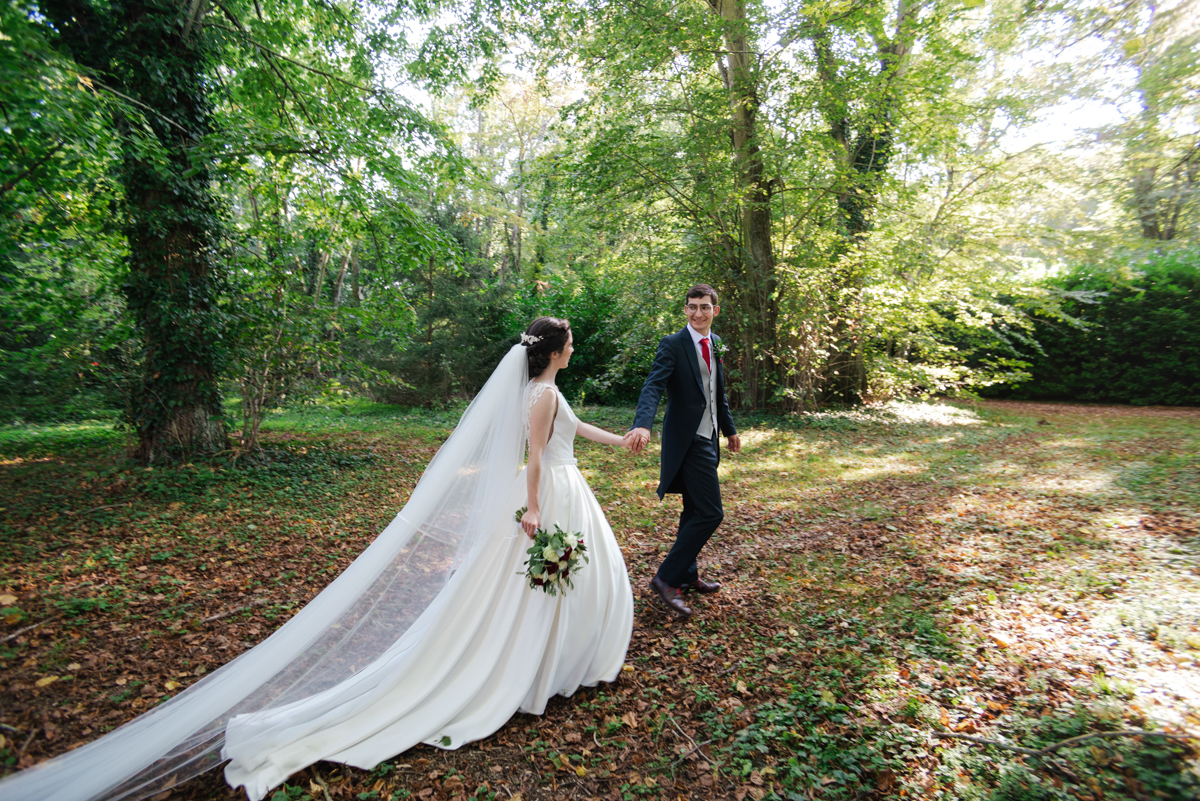 Bride and groom walking hand in hand through the forest at a Loire Valley wedding