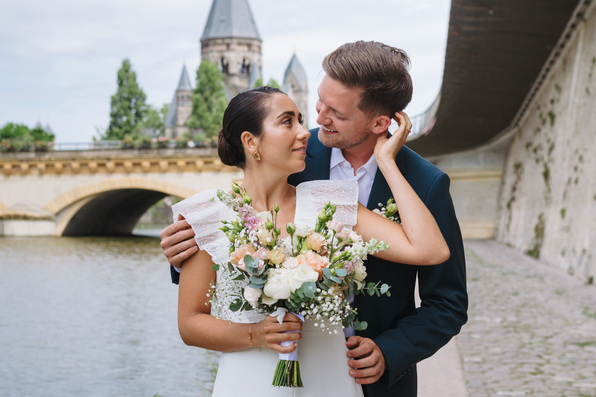 Couple embracing by the river with a bridge in the background